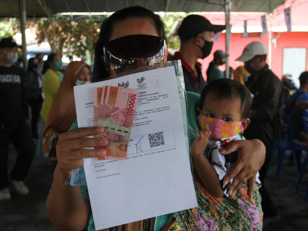 Warga menunjukkan uang Bantuan Sosial Tunai (ANTARA FOTO/Didik Suhartono)