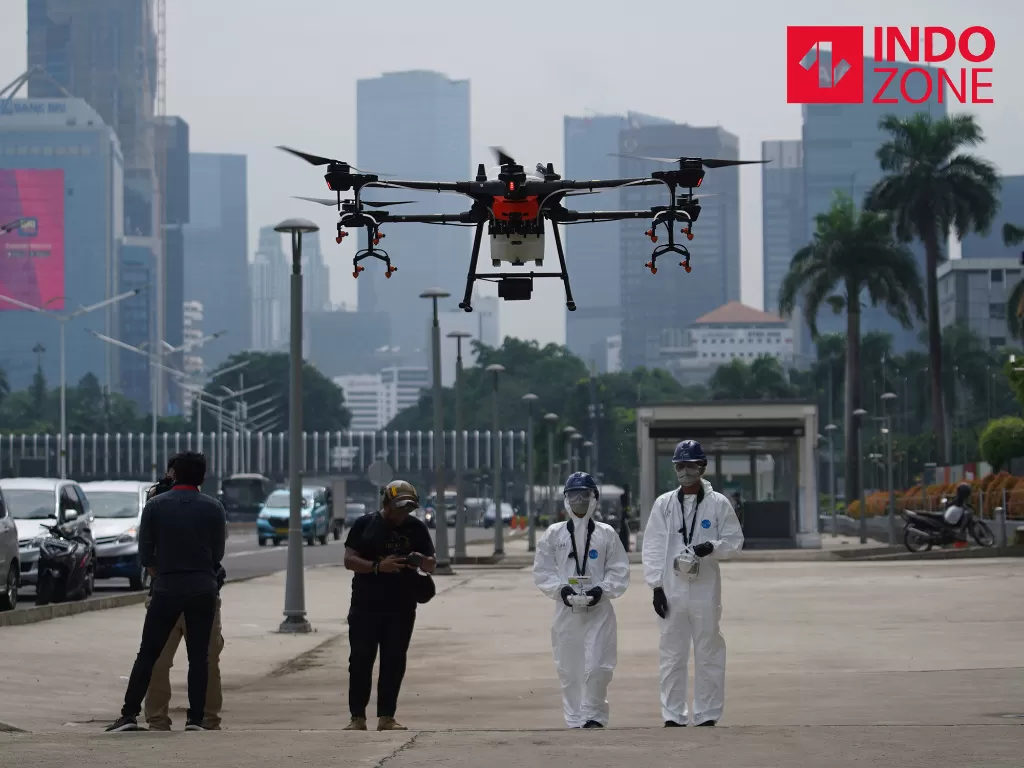 Petugas mengendalikan drone yang berisi cairan disinfektan untuk basmi Covid-19 di kawasan Jalan Sudirman, Jakarta. (INDOZONE).
