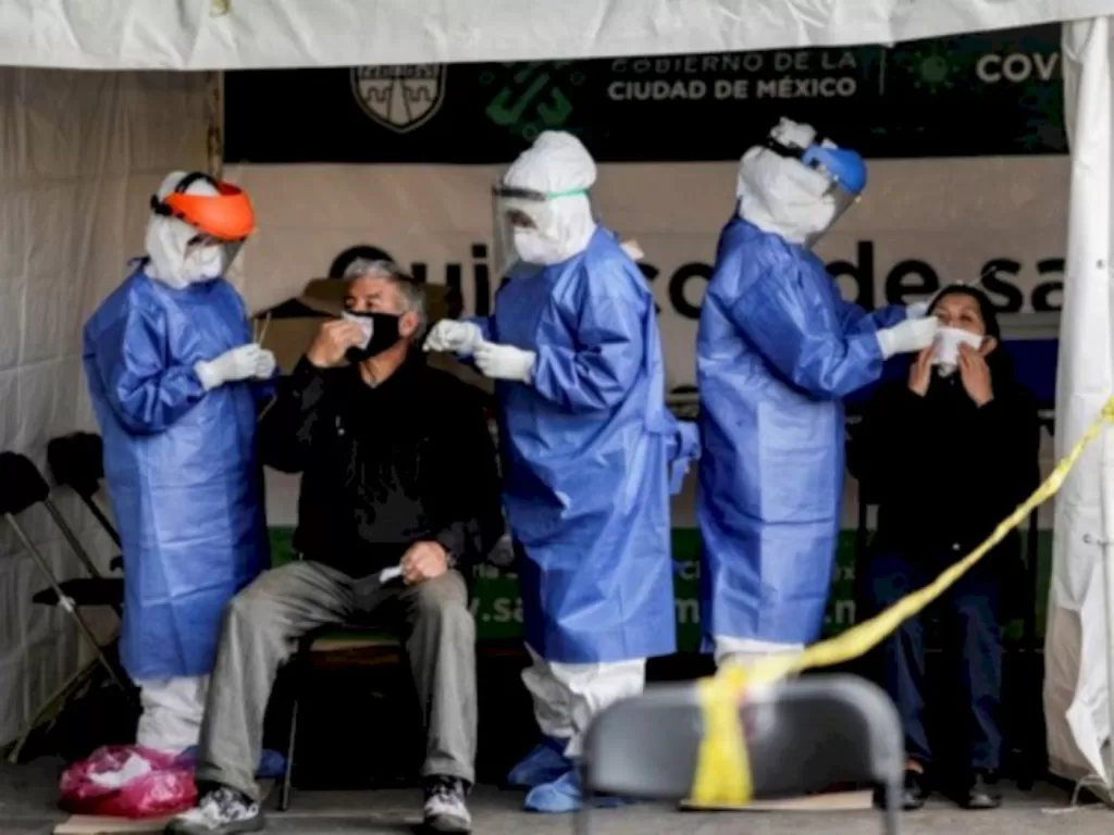 Petugas kesehatan mengambil sampel usap dari seorang pria dan wanita untuk tes Covid-19 di Mexico City, Meksiko (6/11/2020). (REUTERS/Henry Romero)