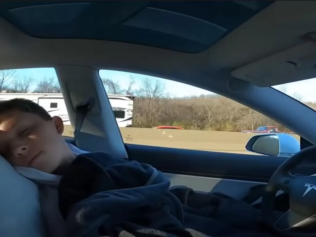 Tampilan pria yang nekat tidur ketika mengendarai Tesla Model 3. (photo/SS/Youtube/Mr. Hub)