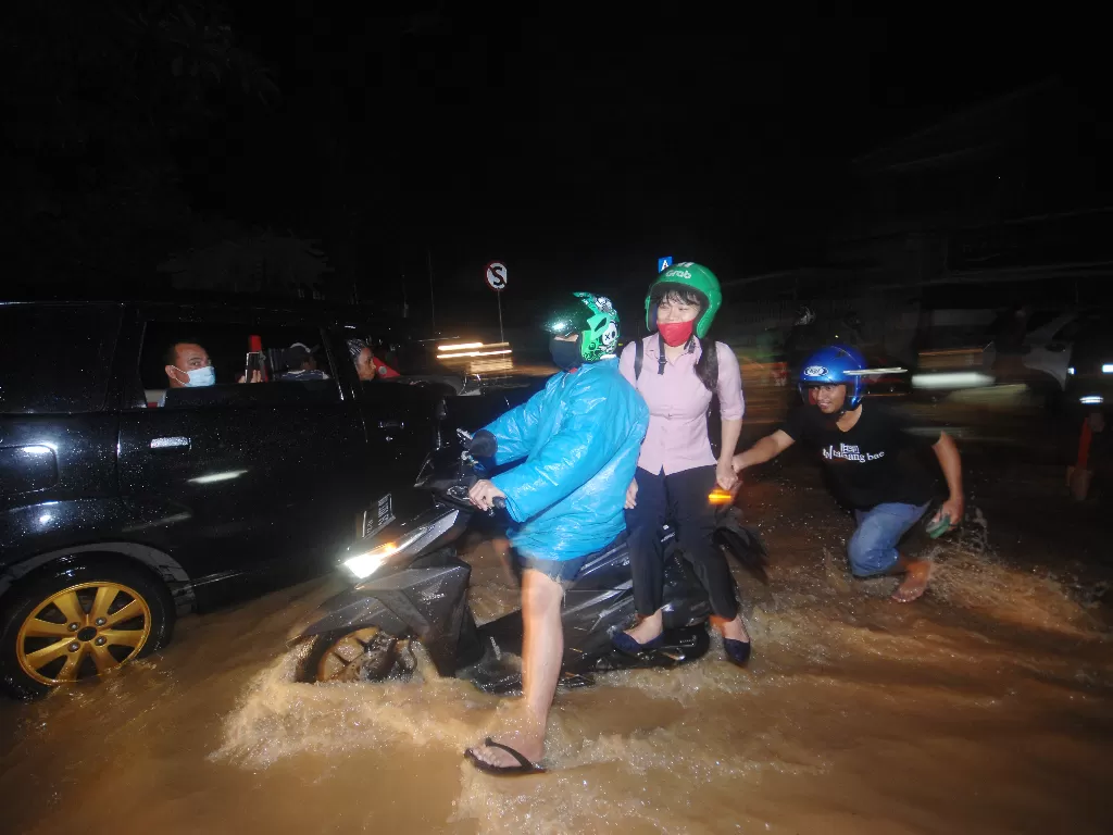 Warga menerobos banjir di salah satu ruas jalan di Kota Manado, Sulawesi Utara, Jumat (22/1/2021). (Antara Foto)