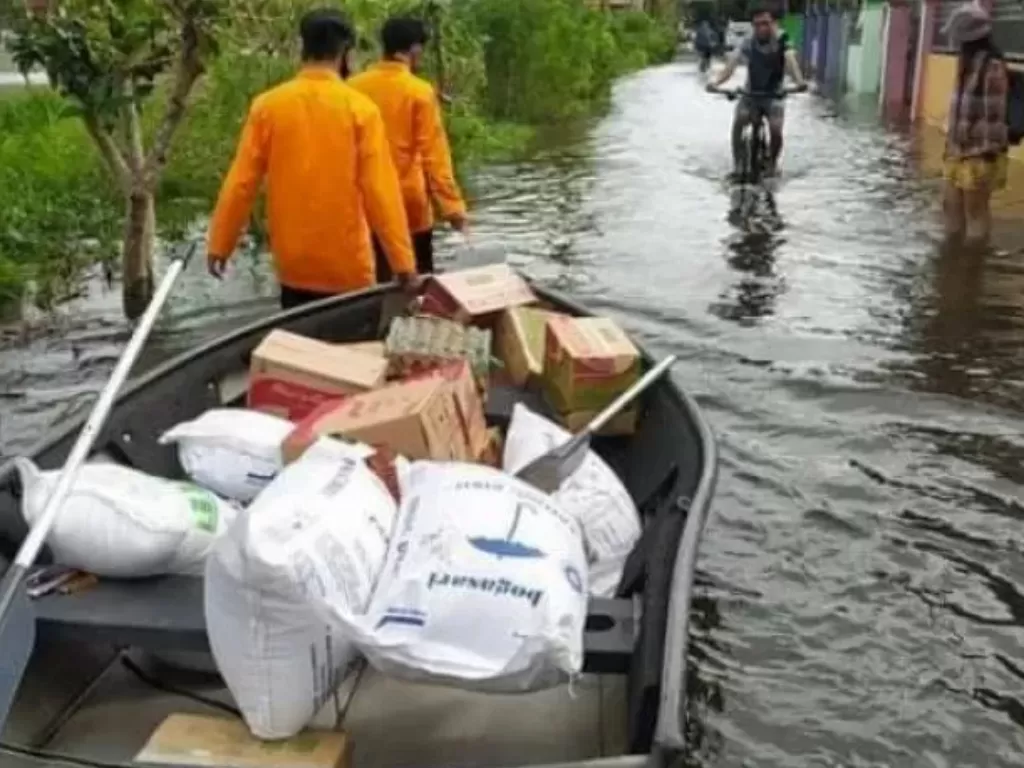 Para anggota BPBD Kota Banjarmasin, Kalsel, Rabu (20/1/2021) menggunakan perahu saat mengantar bantuan untuk warga terdampak banjir (Antara)