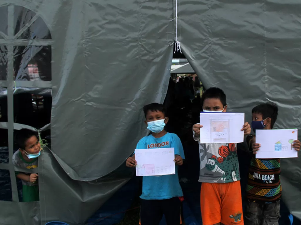 Sejumlah anak memperlihatkan gambar saat mengikuti pembelajaran di tenda pengungsian Stadion Manakarra, Mamuju, Sulawesi Barat, Sabtu (23/1/2021). (Photo/ANTARA FOTO/Akbar Tado)