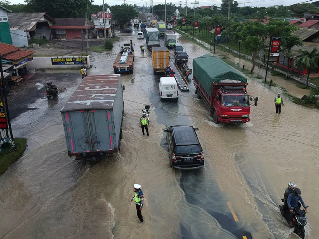 Foto udara kendaraan melintas digenangan banjir di jalur Pantura Kedungkelor, Kabupaten Tegal, Jawa Tengah, Kamis (14/1/2021). (Photo/ANTARA FOTO/Oky Lukmansyah)