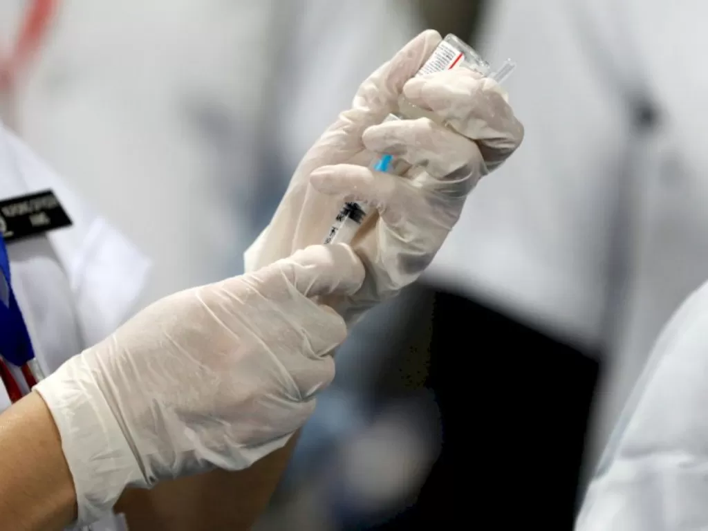 Ilustrasi. Seorang petugas kesehatan mengisi jarum suntik dengan dosis vaksin COVID-19. (photo/REUTERS / Adnan Abidi)