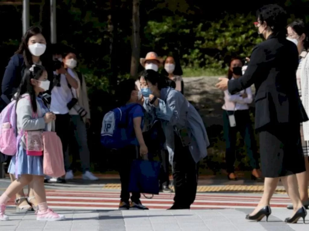 Dengan menggunakan masker seorang ibu mencium anaknya di TK di Seoul, Korea Selatan (27/5/2020). (Yonhap News Agency via REUTERS)