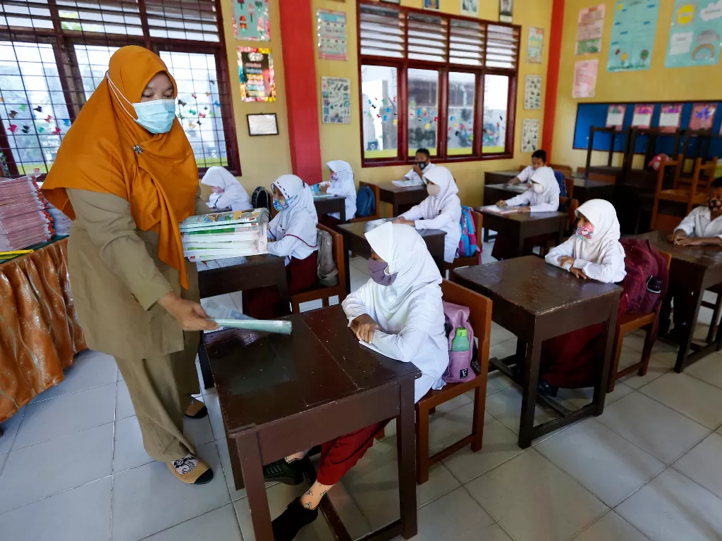 Guru membagikan buku pelajaran kepada pelajar pada hari pertama sekolah tatap muka di SD Negeri 42, Banda Ace (Ilustrasi/ANTARA FOTO/Irwansyah Putra)