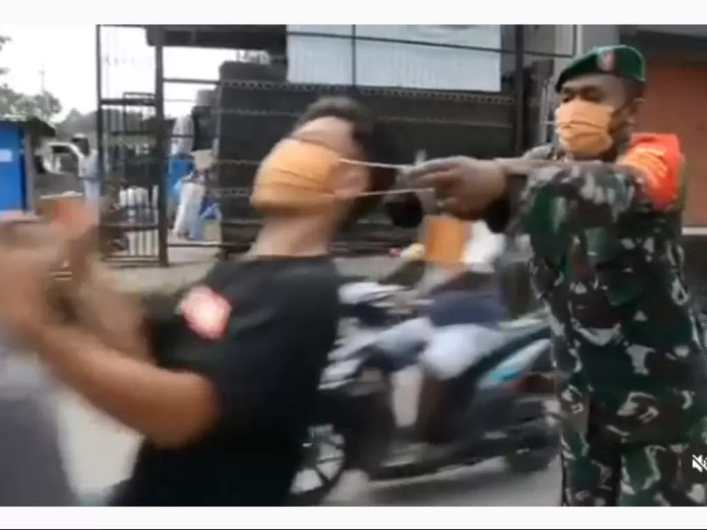 Seorang pemuda yang sedang dipasangi masker oleh anggota TNI tiba-tiba tertarik karena motornya jalan (Istimewa)