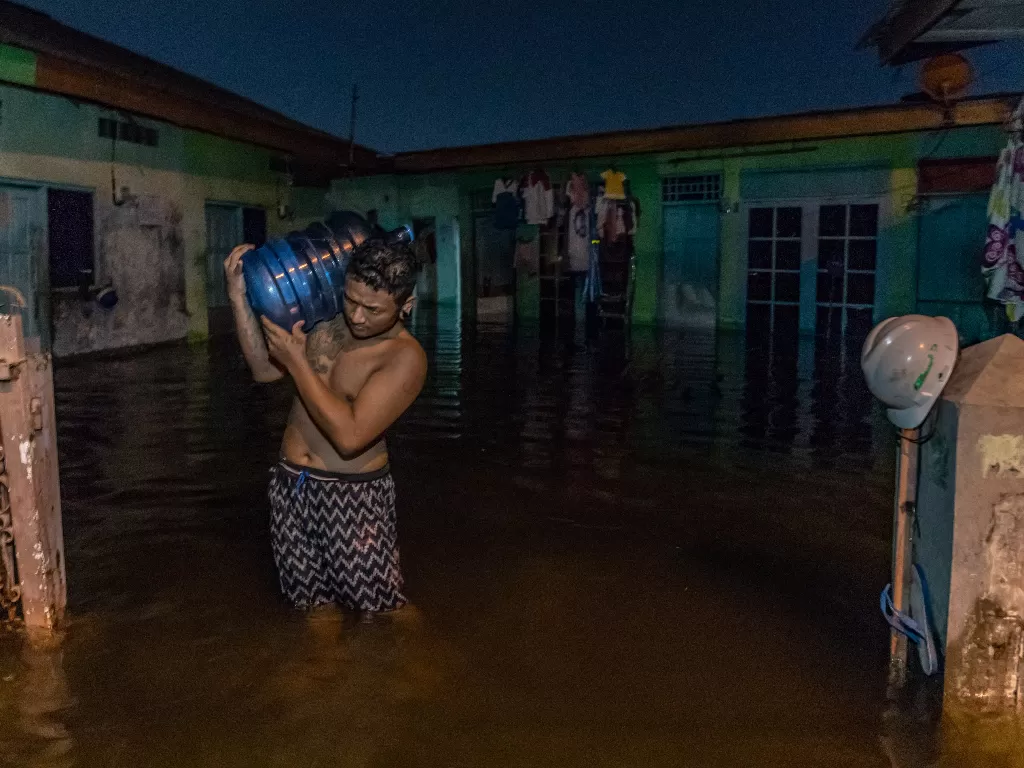 Seorang warga memikul galon air untuk kebutuhan air minum keluarganya yang mengungsi akibat banjir di Kelurahan Tanjung Mas, Semarang, Jawa Tengah, Sabtu (6/2/2021).  (photo/ANTARA FOTO/Aji Styawan)
