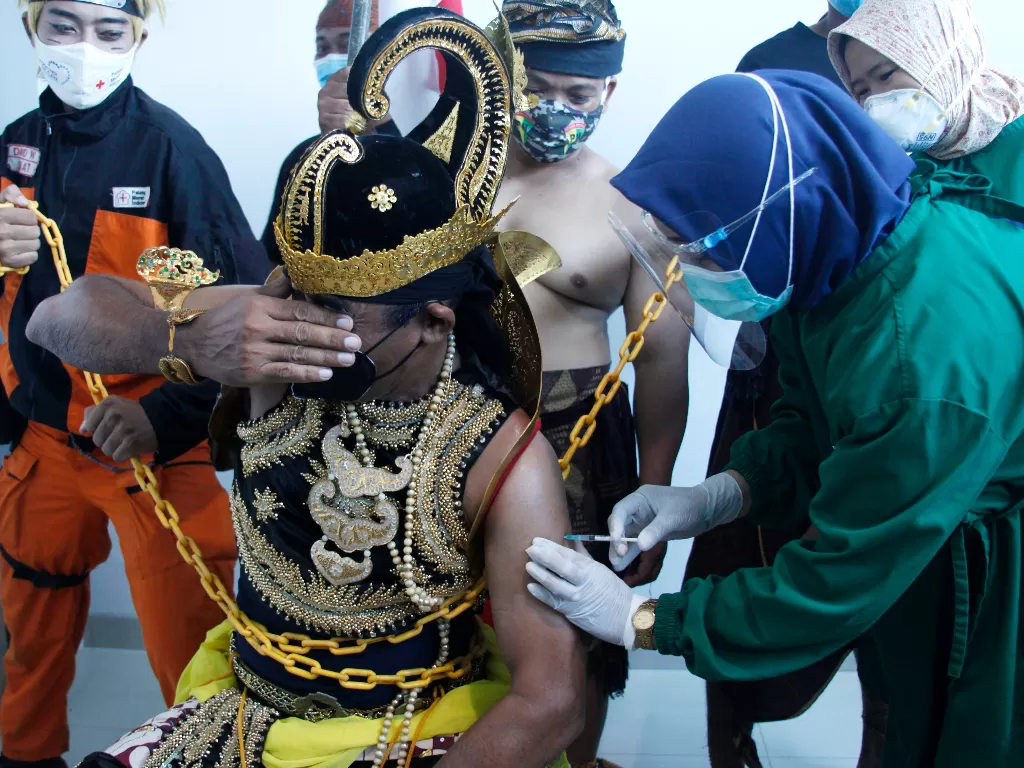 Petugas medis menyuntikkan vaksin COVID-19 kepada penerima berkostum wayang (ANTARA FOTO/Maulana Surya)