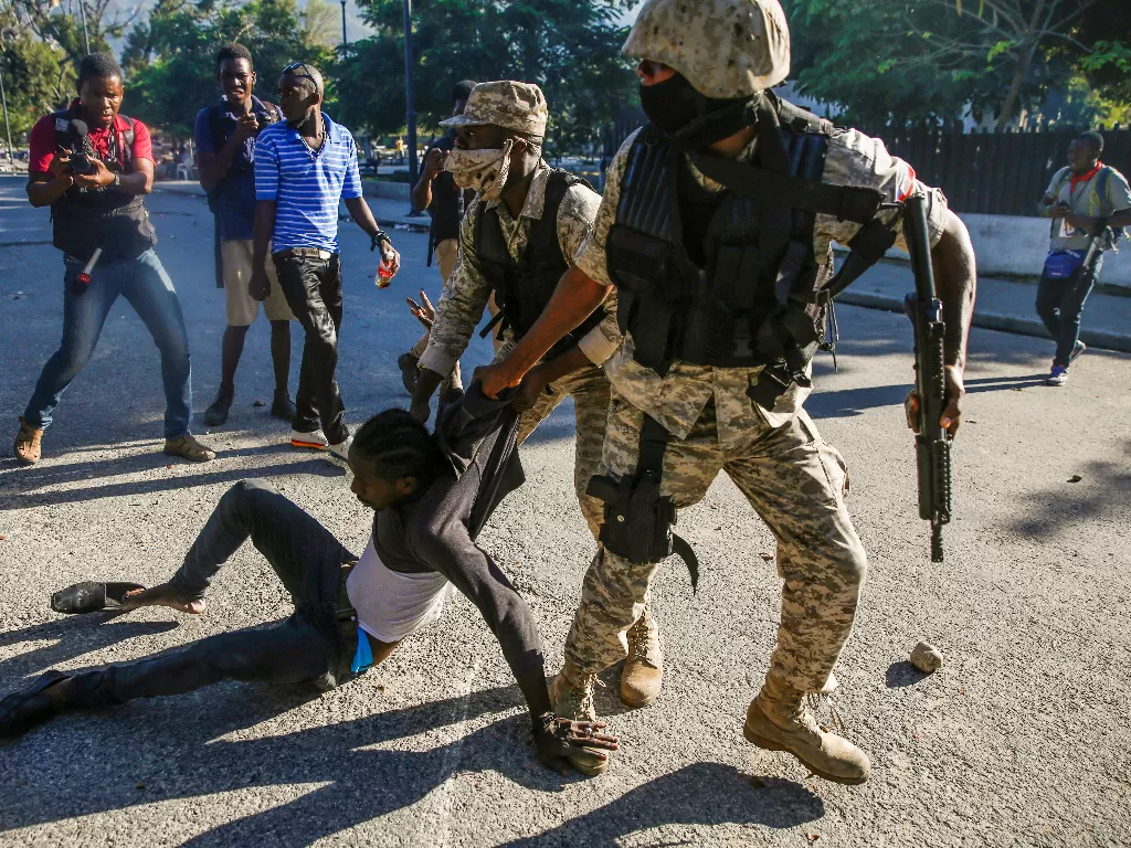 Petugas polisi menahan seorang pria selama protes terhadap Presiden Haiti Jovenel Moise (REUTERS/Jeanty Junior Augustin)