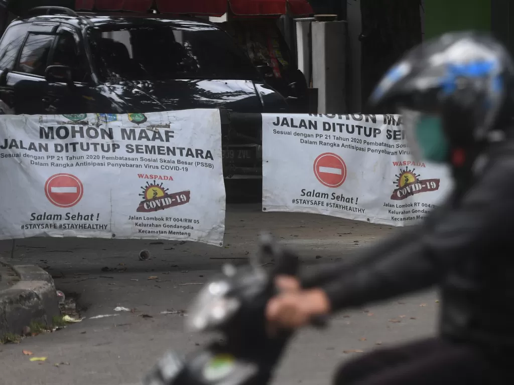 Warga melintasi pagar karantina wilayah saat pemberlakuan pembatasan kegiatan masyarakat (PPKM) skala mikro hari pertama di kawasan Menteng, Jakarta, Selasa (9/2/2021). (ANTARA FOTO/Akbar Nugroho Gumay)