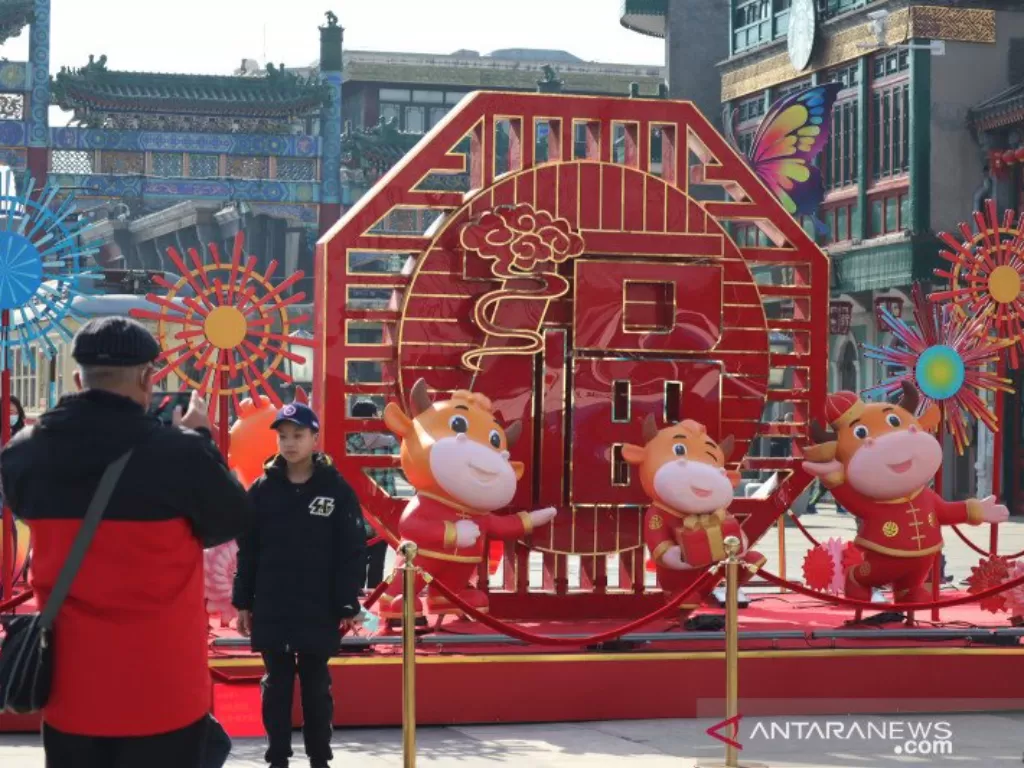 Warga Kota Beijing berfoto di depan dekorasi bertema Imlek di pusat jajanan kuno kawasan Qianmen pada hari pertama liburan Tahun Baru China di Beijing, Tiongkok, Rabu (10/2/2021). (ANTARA FOTO/M. IRFAN ILMIE)