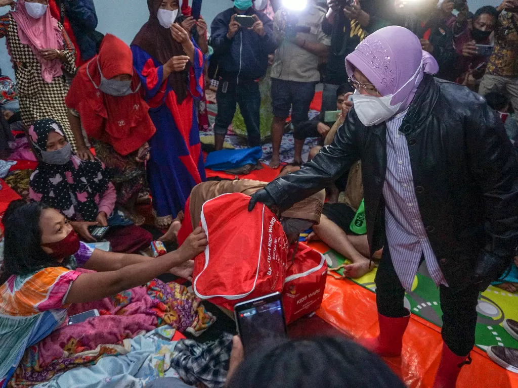 Menteri Sosial Tri Rismaharini (kanan) memberikan bantuan kepada warga terdampak banjir di tempat pengungsian SD Muhammadiyah Bener, Kabupaten Pekalongan, Jawa Tengah. (photo/ANTARA FOTO/Harviyan Perdana Putra)