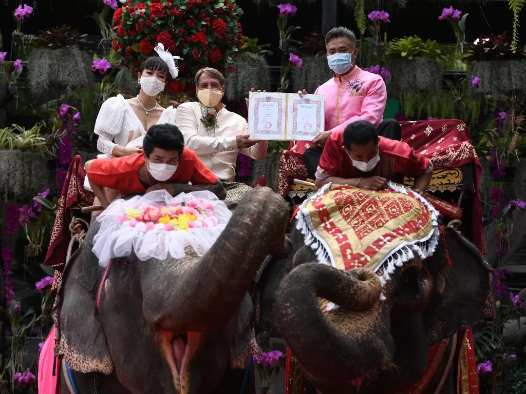  Pasangan menerima surat nikah saat menunggangi gajah di Hari Valentine, Nong Nooch Tropical Garden di provinsi Chonburi, Thailand, 14 Februari 2021. (photo/REUTERS/Chalinee Thirasupa)