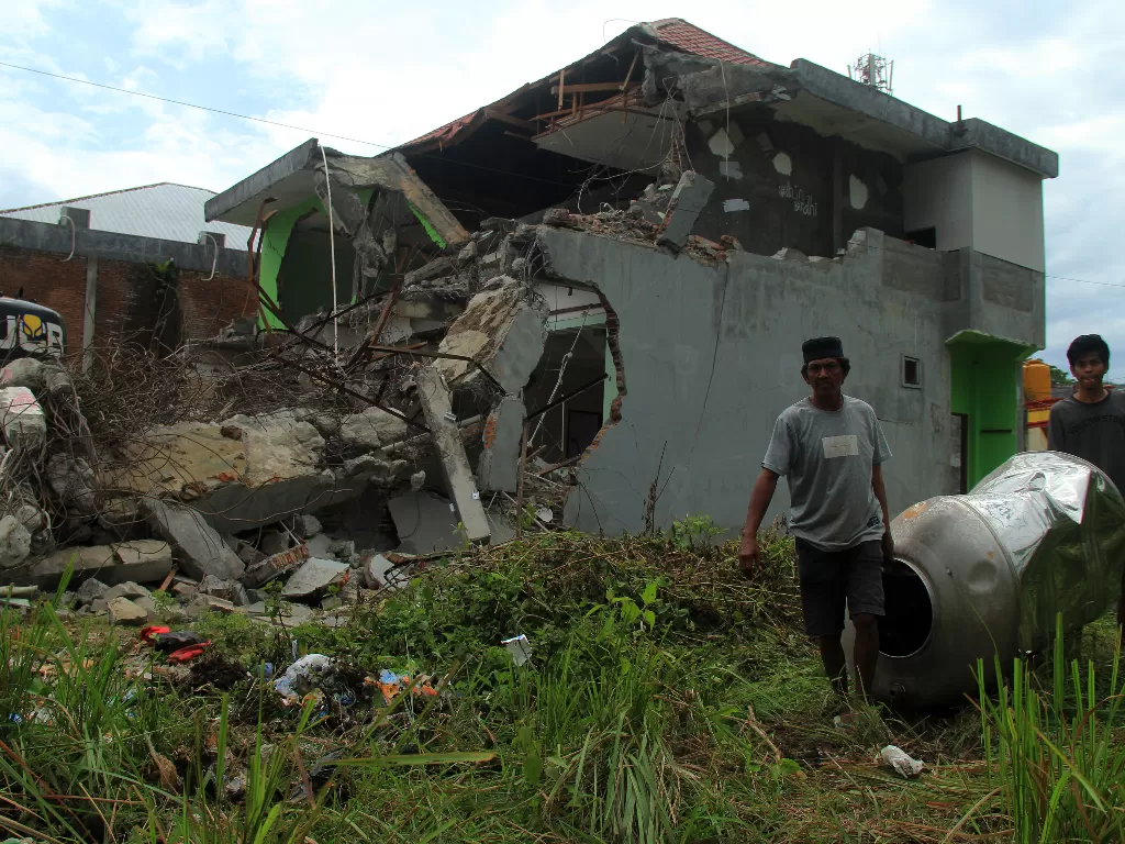 Warga mengambil barang dari sisa reruntuhan bangunan pascagempa bumi. (Foto: ANTARA/Akbar Tado)
