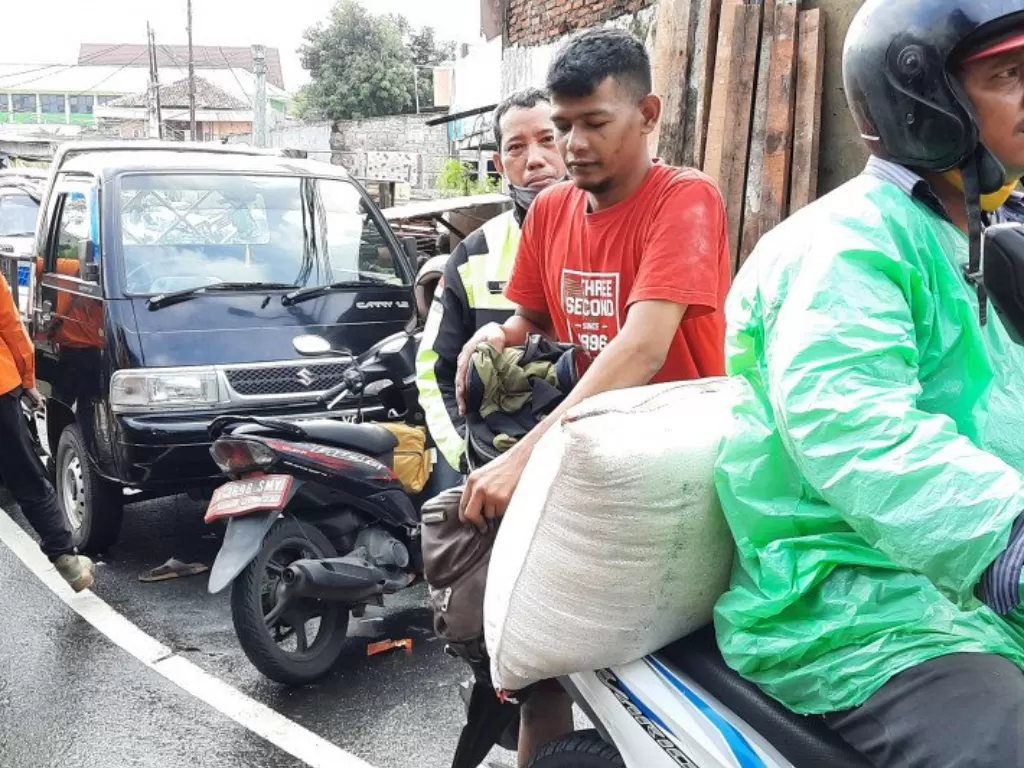 Bukhari (27) mengevakuasi beras dari toko miliknya menggunakan sepeda motor, sebanyak 300 kilogram beras miliknya rusak terendam banjir di Jakarta Selatan, Sabtu (20/2/2021). (photo/ANTARA/Laily Rahmawaty)