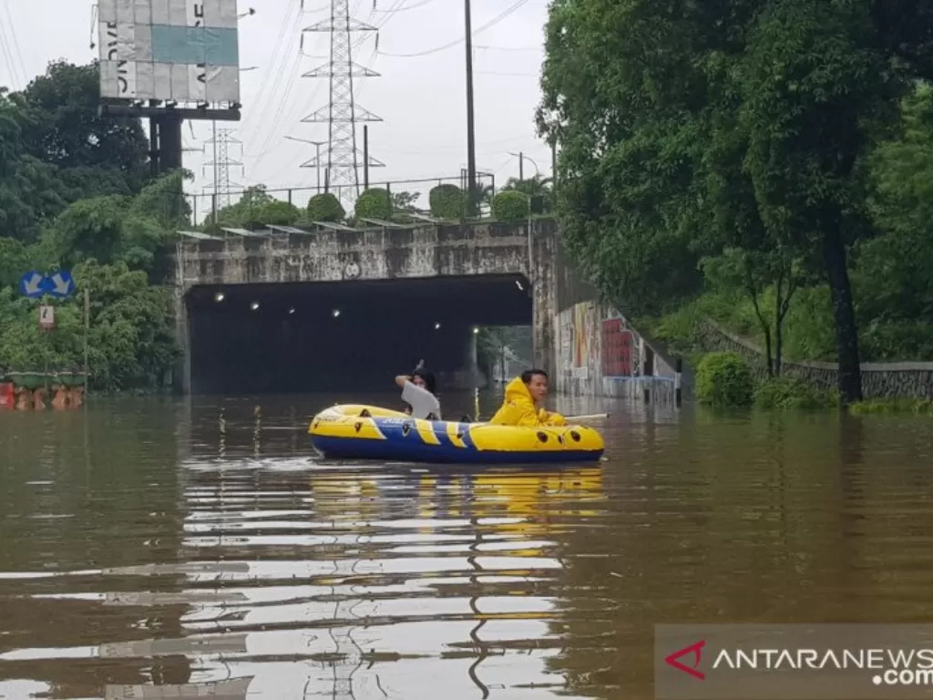 Warga memanfaatkan jasa penyewaan perahu karet untuk melintas di sekitar terowongan Tol Cawang di Jalan DI Panjaitan yang terendam banjir, Sabtu (20/2/2021). (ANTARA/HO-Lantas Polrestro Jaktim).