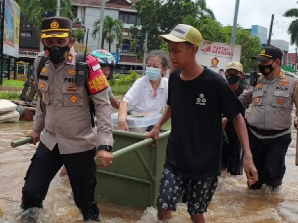 Kapolsek Kembangan Polres Metro Jakarta Barat Kompol H Khoiri membantu evakuasi wanita lanjut usia. (dok Humas Polres Metro Jakarta Barat)