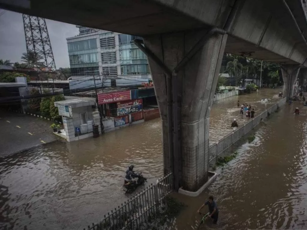 Warga melintasi berjalan banjir di Jalan Kapten Tendean, Mampang Prapatan, Jakarta, Sabtu (20/2/2021). (ANTARA FOTO/Aprillio Akbar)
