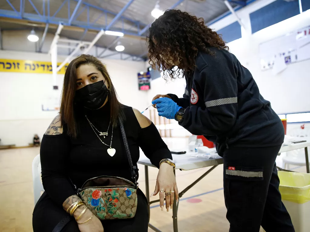 Seorang wanita divaksinasi COVID-19 di pusat vaksinasi sementara di sebuah lapangan olahraga di Tel Aviv, Israel 16 Februari 2021. (photo/REUTERS/Corinna Kern)