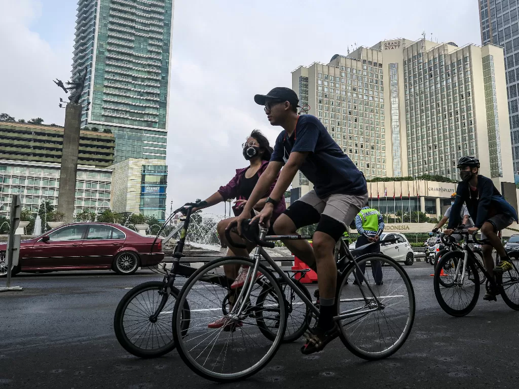 Warga bersepeda melintasi kawasan Bundaran Hotel Indonesia di Jakarta, Minggu (14/2/2021). (photo/ANTARA FOTO/M Risyal Hidayat)