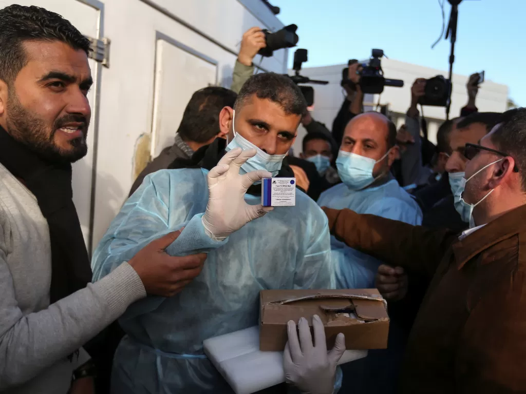 Seorang petugas kesehatan Palestina menunjukkan sekotak vaksin Sputnik V Rusia yang dikirim oleh Uni Emirat Arab, di tengah wabah Covid-19, di perlintasan Rafah di Jalur Gaza selatan, Minggu (21/2/2021). (REUTERS/Ibraheem Abu Mustafa)