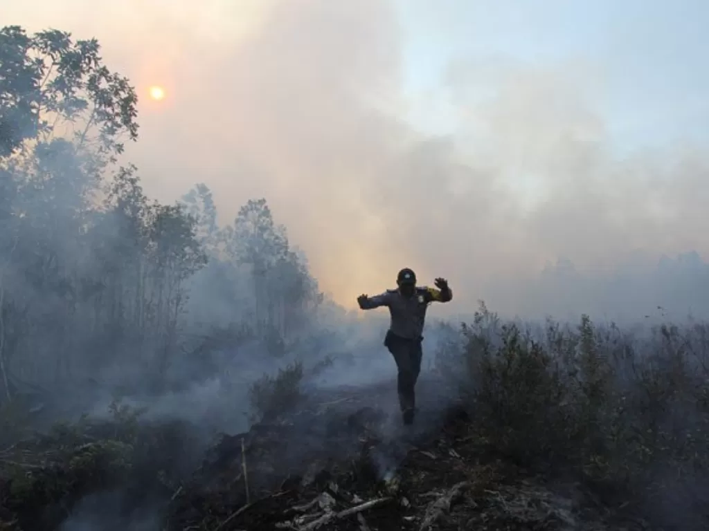 Ilustrasi: Seorang polisi meloncat untuk menghindari area di lahan gambut yang terbakar di Desa Teluk Makmur, kecamatan Medang Kampai, Dumai, Riau. (ANTARA FOTO/Aswaddy Hamid/aww) 