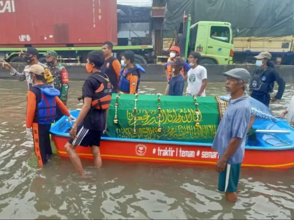 Petugas gabungan menggunakan perahu untuk membawa jenazah warga yang akan dimakamkan saat melintasi kawasan banjir (Antara)