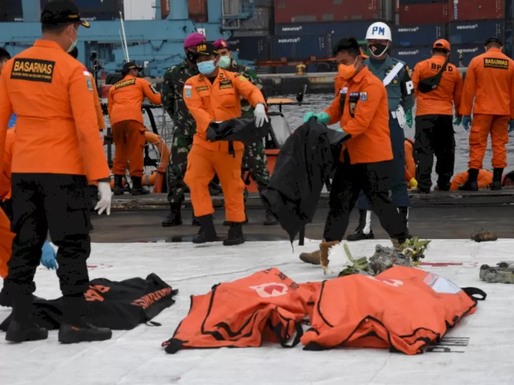 Anggota Basarnas membawa kantong jenazah berisi objek temuan dari lokasi jatuhnya pesawat Sriwijaya Air SJ 182 di Dermaga JICT II, Tanjung Priok, Jakarta Utara, Minggu (17/1/2021). (photo/ANTARA FOTO/Indrianto Eko Suwarso)