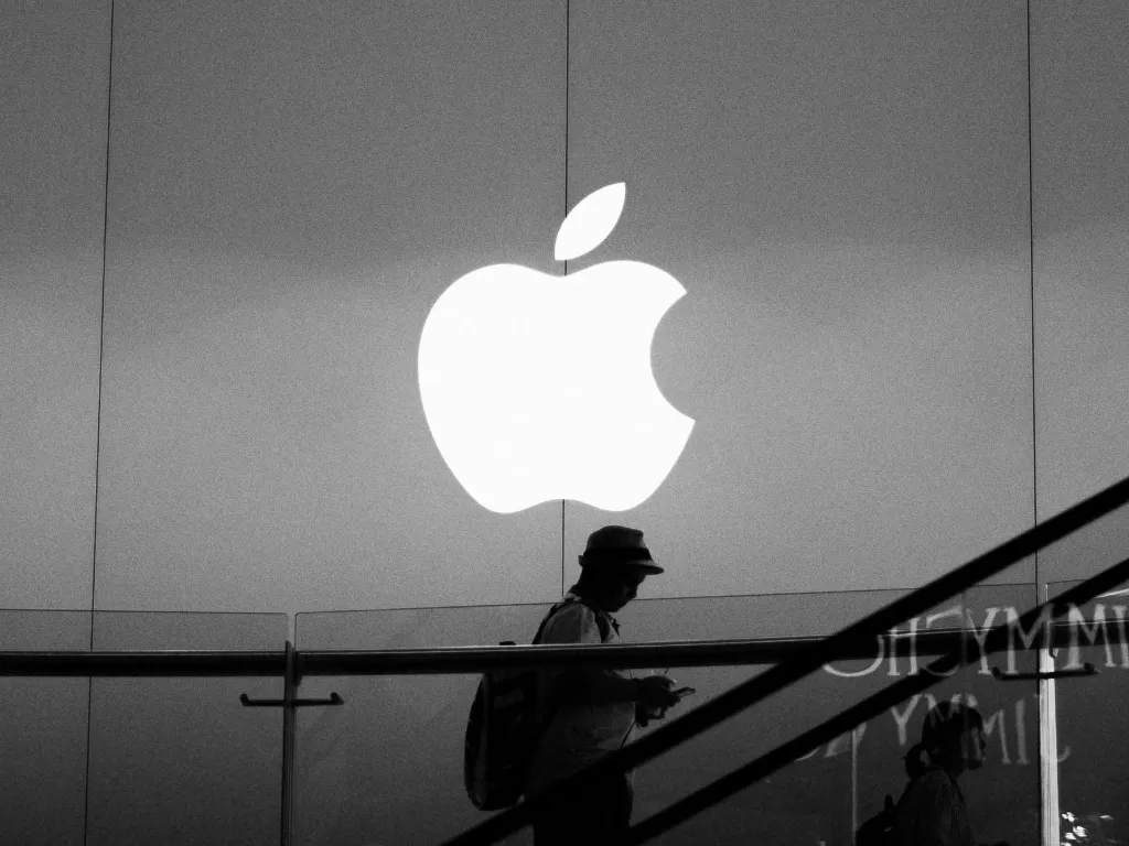 Seorang pria berada di depan logo Apple di sebuah Apple Store (photo/Unsplash/Alireza Khoddam)