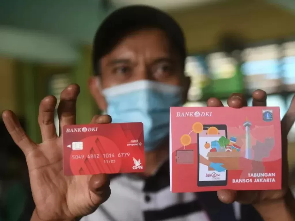 Warga menunjukan buku tabungan dan kartu debit usai mengambil Bantuan Sosial Tunai (BST. (ANTARA FOTO/Akbar Nugroho Gumay)