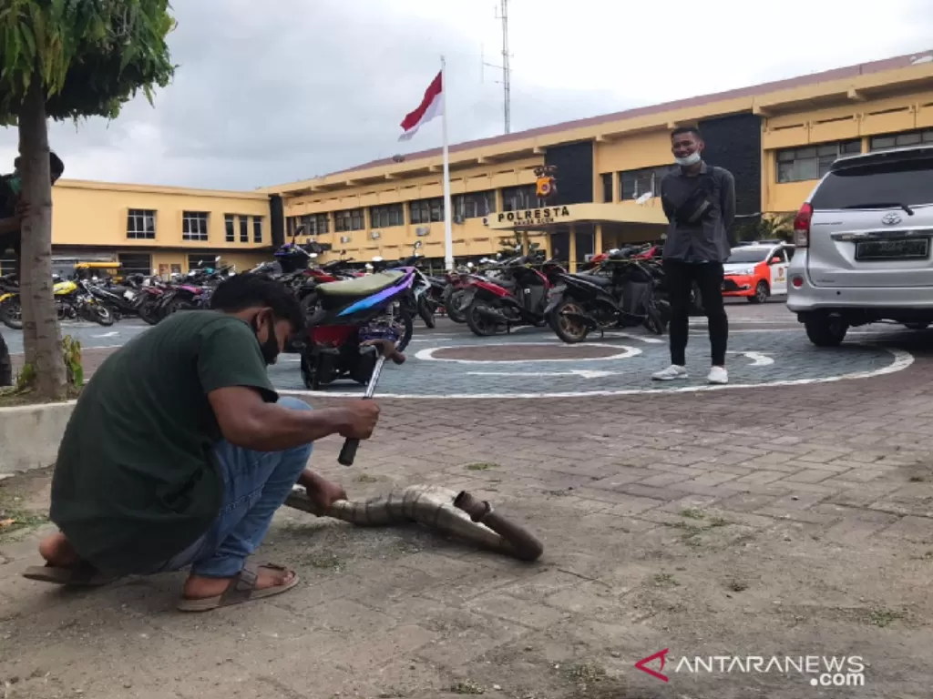 Seorang remaja merusakkan knalpot blong miliknya sendiri usai tertangkap balapan liar, di Markas Polresta Banda Aceh, Kamis (25/2/2021) (photo/ANTARA/HO)