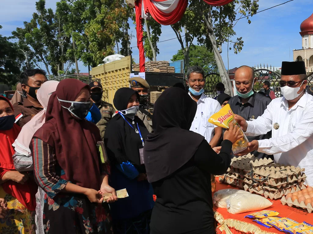 Bupati Aceh Barat Ramli MS (kanan) menyerahkan barang kebutuhan pokok kepada pembeli (ANTARA FOTO/Syifa Yulinnas)