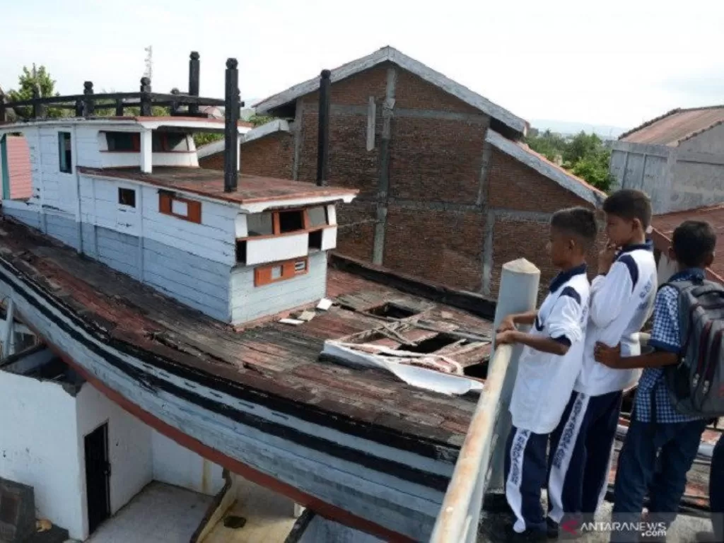 Dokumentasi. Pelajar membayangkan dahsyatnya tsunami Aceh tahun 2004, saat menyaksikan situs Kapal Tsunami Atas Rumah, di Desa Lampulo, Banda Aceh, Aceh, Rabu (11/12/2019). (photo/ANTARA FOTO/Ampelsa)