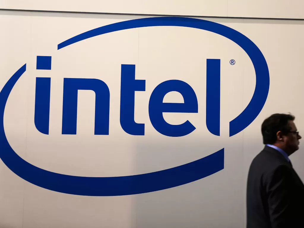 Seorang pria sedang berjalan di depan logo perusahaan Intel (photo/REUTERS/Sergio Perez)