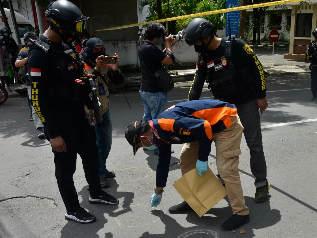 Petugas kepolisian melakukan pemeriksaan di sekitar sisa-sisa ledakan dugaan bom bunuh diri di depan Gereja Katolik Katedral, Makassar, Sulawesi Selatan, Minggu (28/3/2021). (ANTARA FOTO/Abriawan Abhe)