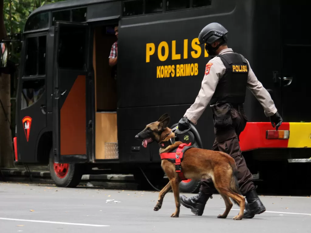 Anggota polisi berjalan dengan anjing pelacak saat mengumpulkan sisa serpihan ledakan bom bunuh diri di depan Gereja Katedral Makassar, Sulawesi Selatan, Senin (29/3/2021). (ANTARA FOTO/Arnas Padda)