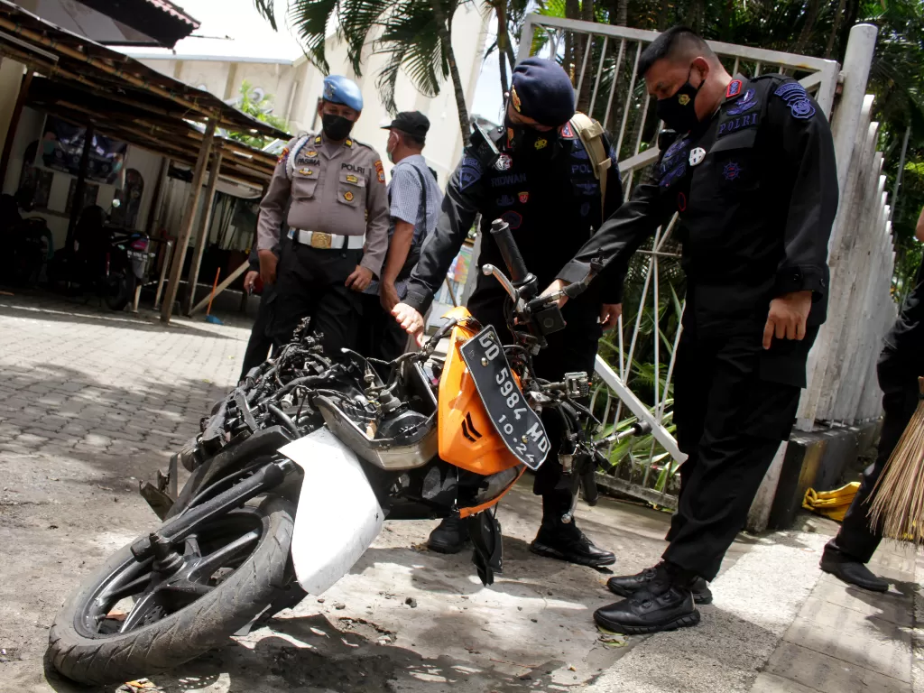 Anggota polisi mengamati motor yang digunakan terduga pelaku bom bunuh diri sebelum dievakuasi di depan Gereja Katedral Makassar, Sulawesi Selatan, Senin (29/3/2021). (ANTARA/Arnas Pada)