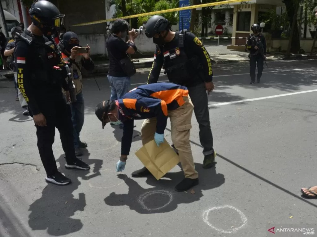 Petugas kepolisian melakukan pemeriksaan di sekitar sisa-sisa ledakan dugaan bom bunuh diri di depan Gereja Katolik Katedral, Makassar, Sulawesi Selatan, Minggu (28/3/2021). (ANTARA FOTO/Abriawan Abhefoc)