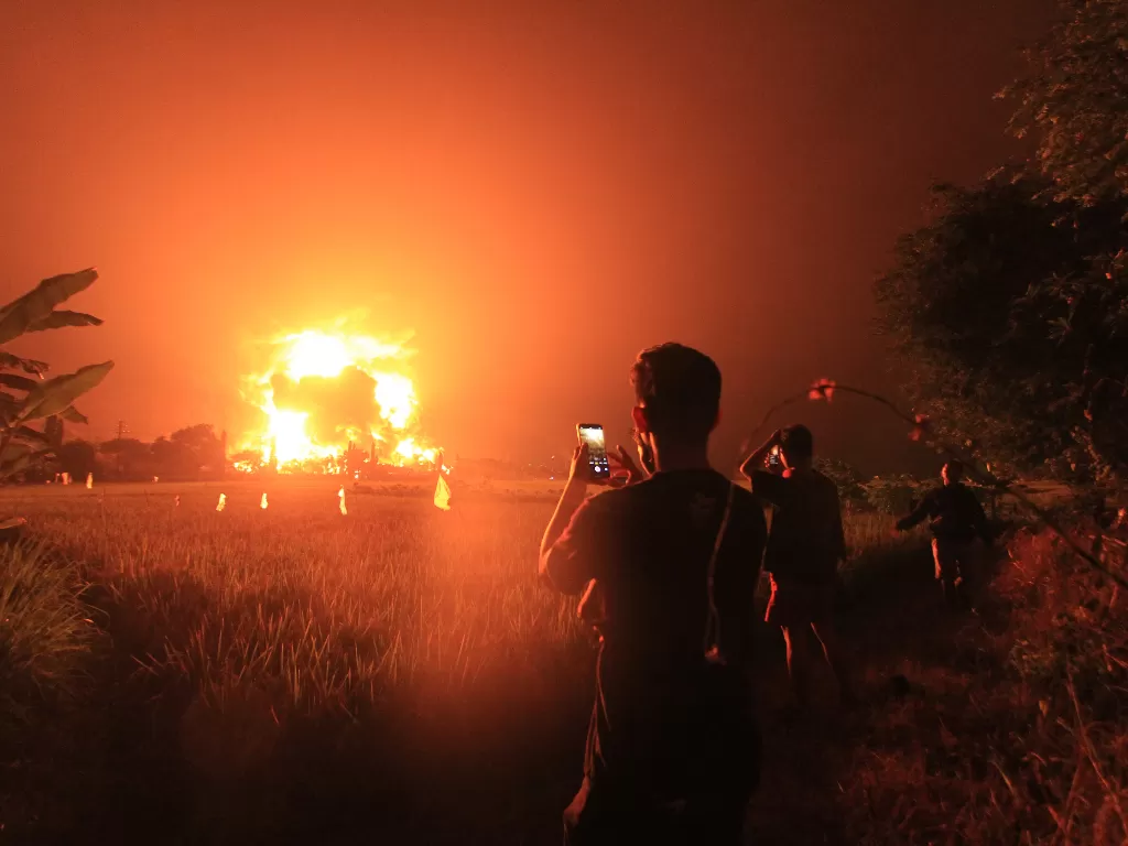 Warga mengambil video dengan gawai miliknya saat terjadi kebakaran di kompleks Pertamina RU VI Balongan, Indramayu, Jawa Barat, Senin (29/3/2021) dini hari. (Foto; ANTARA/Dedhez Anggara)