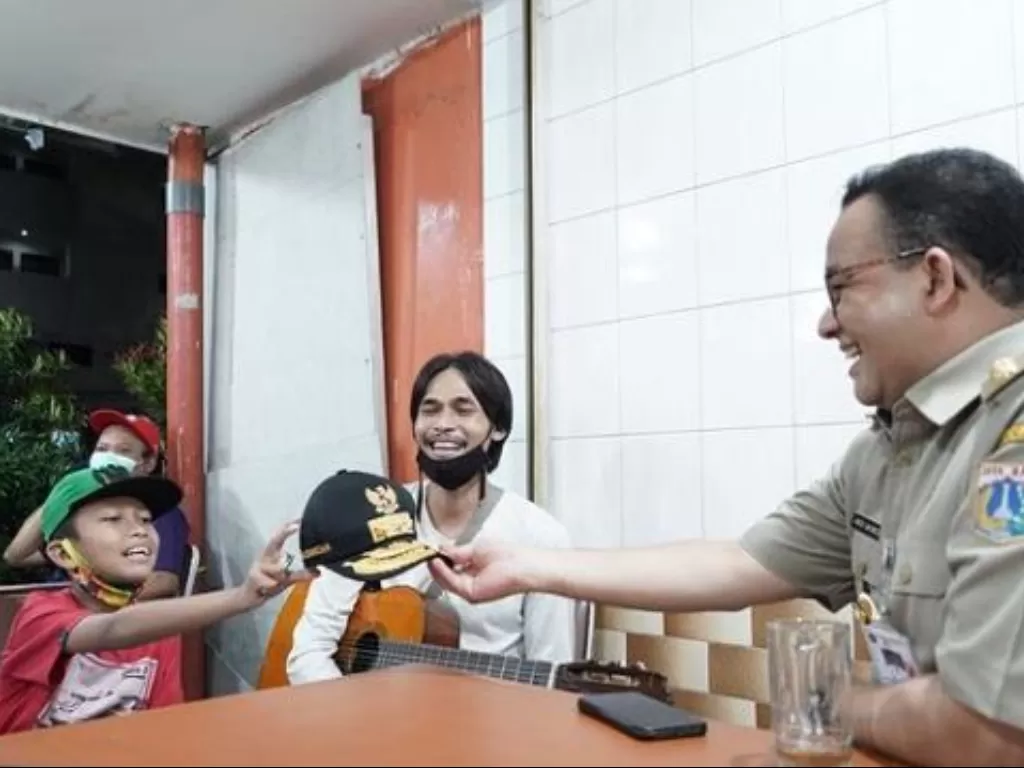 Momen Anies Baswedan beri topi dinas Gubernur DKI Jakarta ke anak pengamen usai santap sate. (Instagram/@aniesbaswedan)