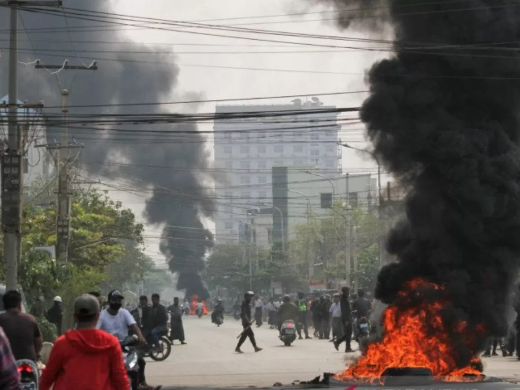 Ban terbakar di sebuah jalan saat protes terhadap kup militer terus berlanjut, di Mandalay, Myanmar, Sabtu (27/3/2021). (REUTERS/Stringer)