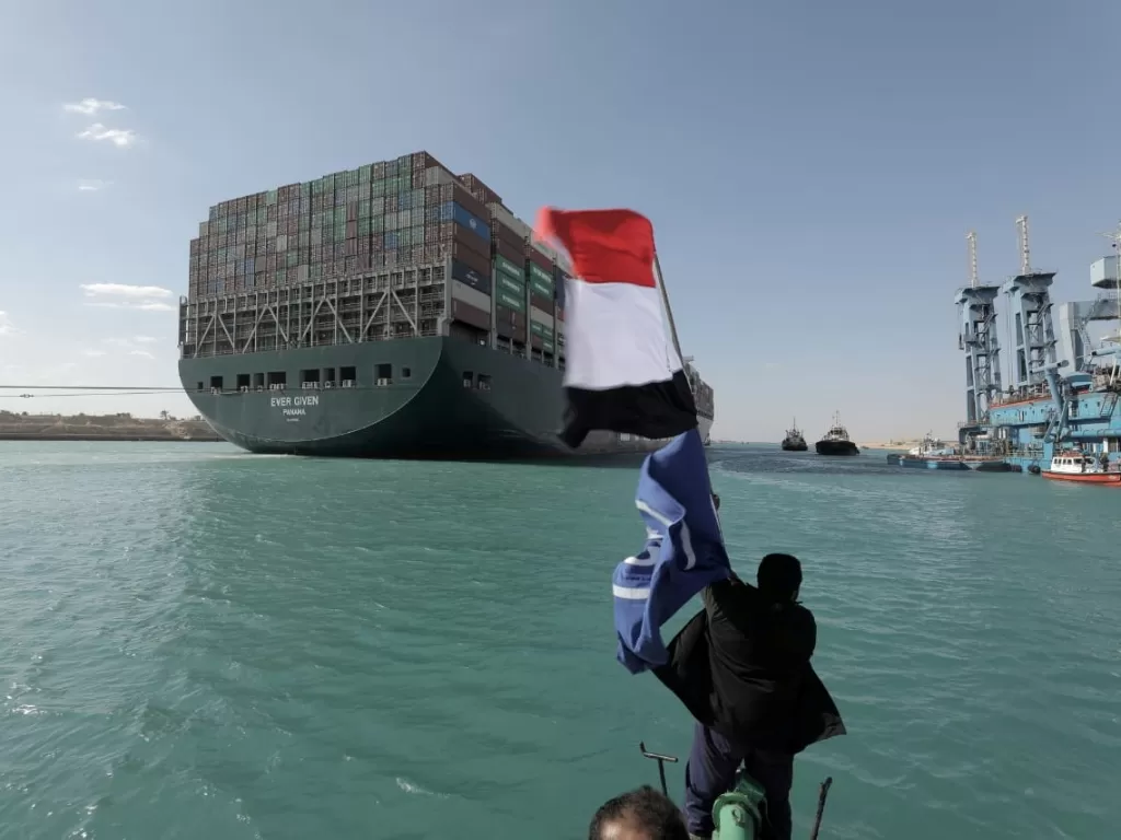 Warga mengibarkan bendera Mesir menyambut bebasnya kapal Ever Given (Suez Canal Authority/Handout via REUTERS)