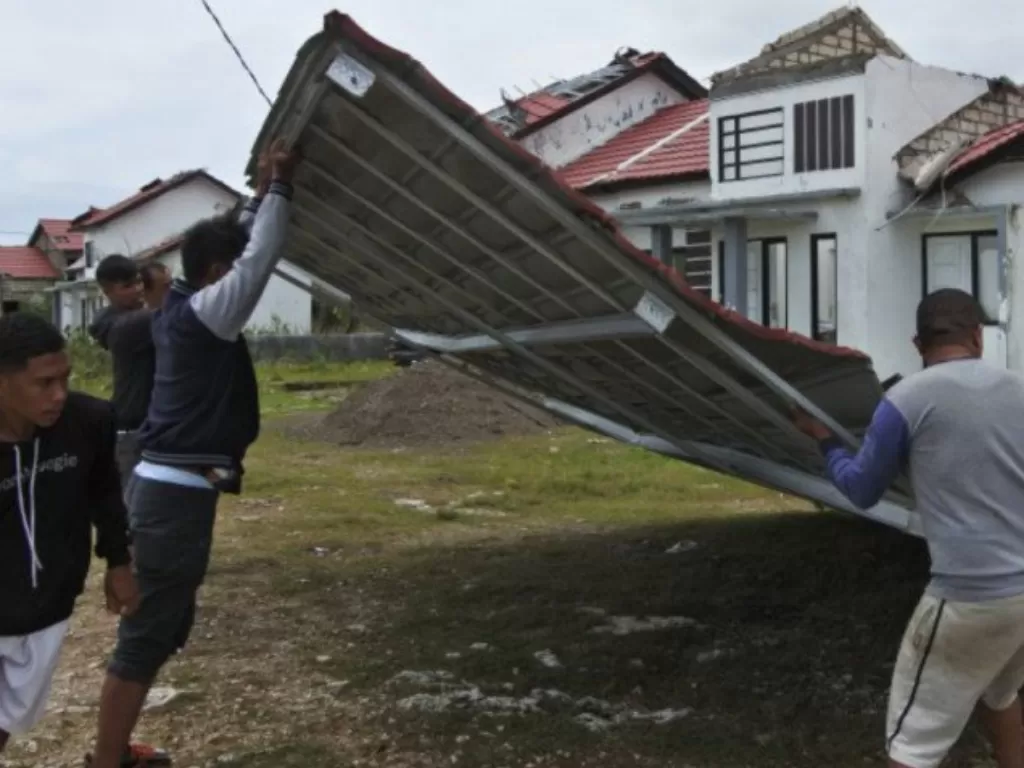 Warga bergotong royong menarik atap rumah yang jatuh di badan jalan akibat diterjang angin kencang di Kota Kupang, NTT, Senin (5/4/2021). (ANTARA/Kornelis Kaha)