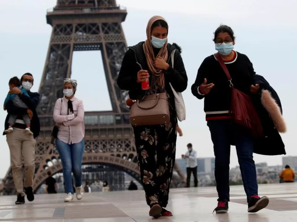 Orang-orang memakai masker di sekitar Menara Eiffer, Paris, Prancis. (REUTERS/Gonzalo Fuentes)