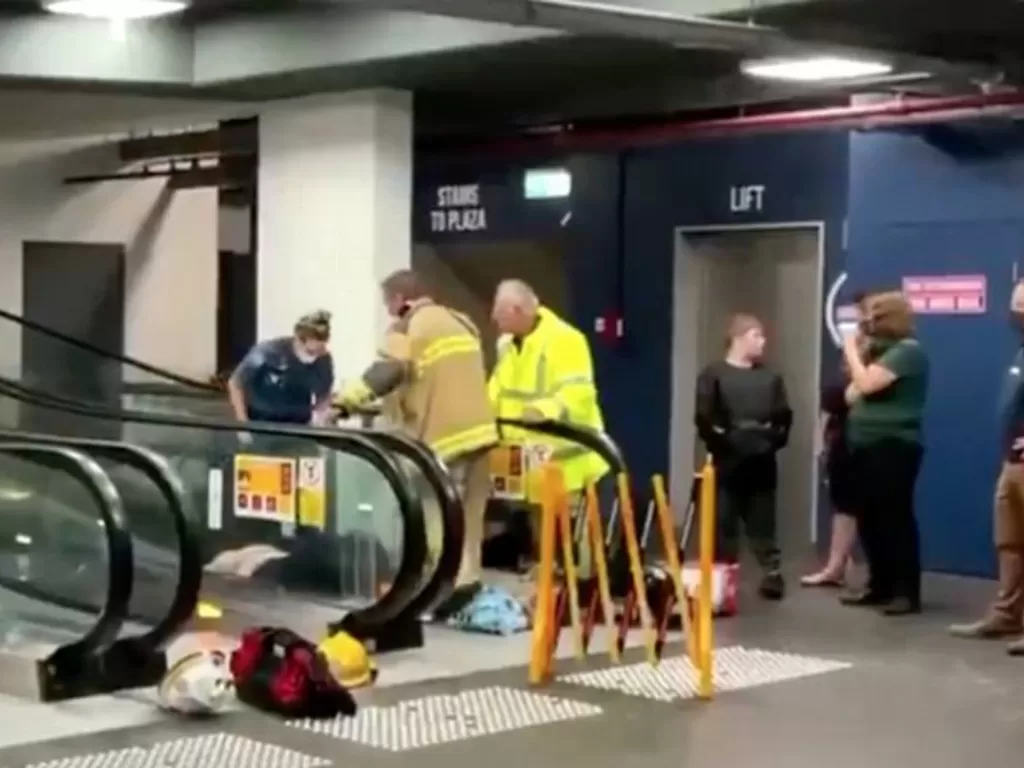 Petugas yang berusaha menyelamatkan wanita yang terjebak di eskalator (Twitter@9NewsGoldCoast)