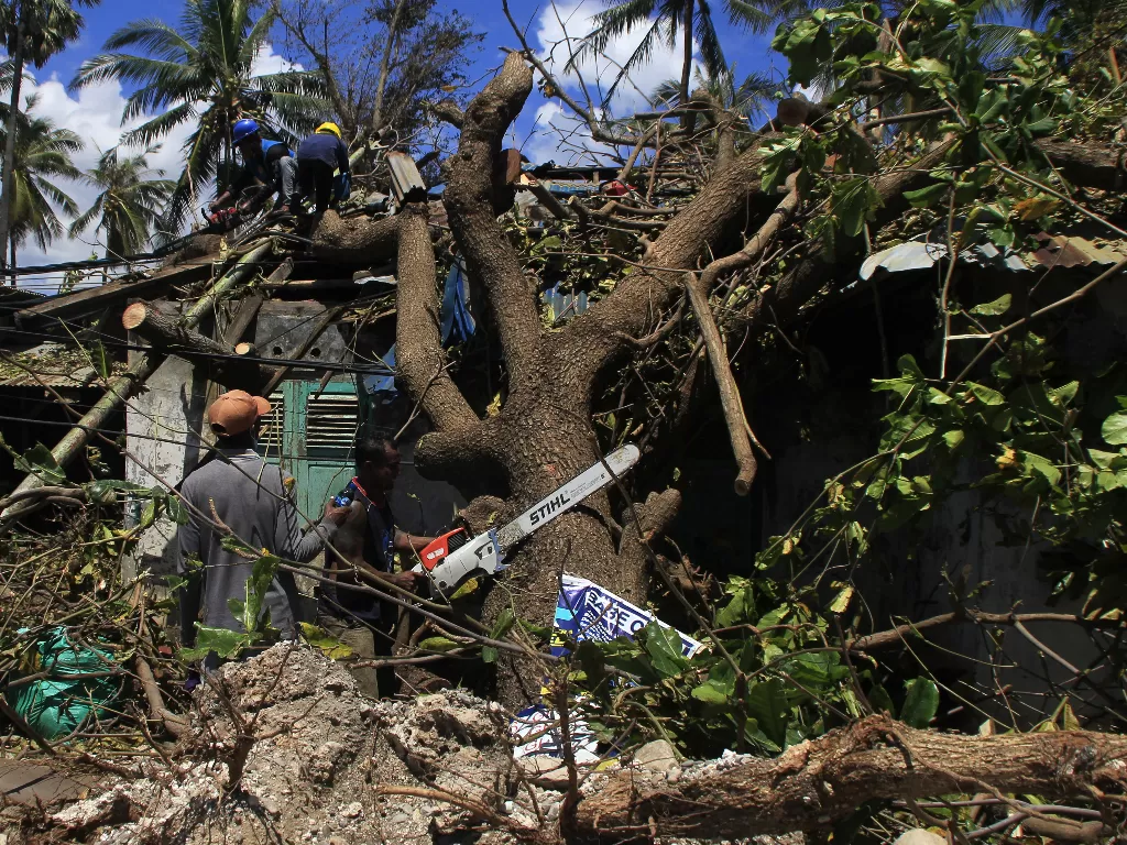 Sejumlah petugas memotong pohon yang tumbang menimpa salah satu rumah (ANTARA FOTO/Kornelis Kaha)