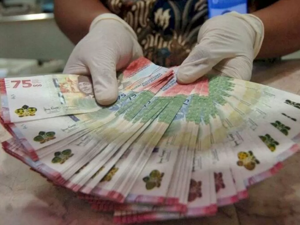 Petugas menunjukkan uang baru pecahan Rp75 ribu. (ANTARA FOTO/Oky Lukmansyah)