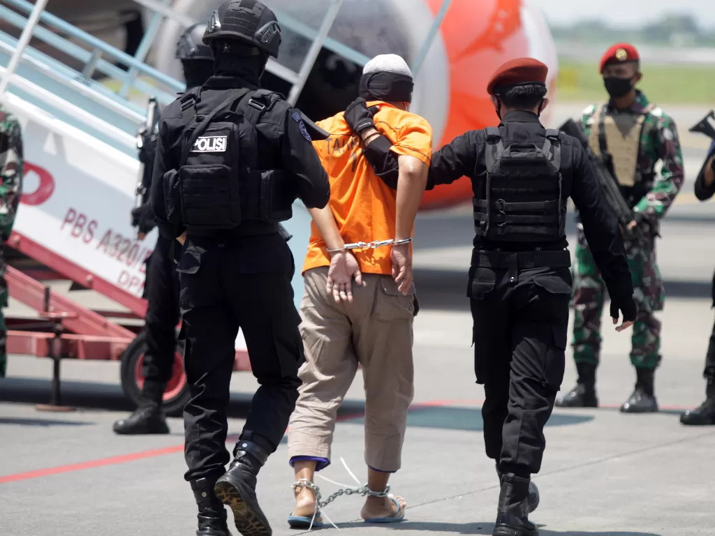 (photo/ANTARA FOTO/Umarul Faruq)Personel Densus 88 Anti Teror membawa terduga teroris menuju ke pesawat udara di Bandara Internasional Juanda, Sidoarjo, Jawa Timur, Kamis (18/3/2021). Sebanyak 22 tahanan kasus terorisme yang berhasil ditangkap Densus 88 A